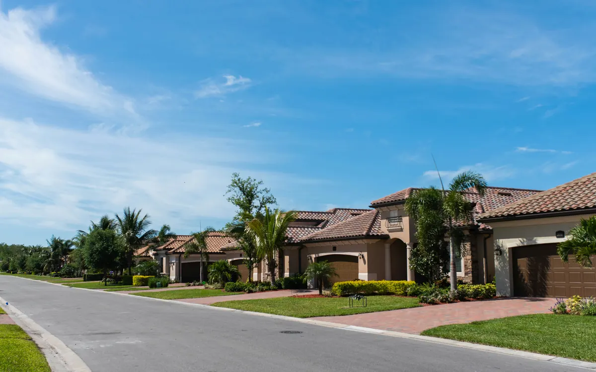 A quiet Southwest Florida street of tile-roof homes with palms and manicured lawns